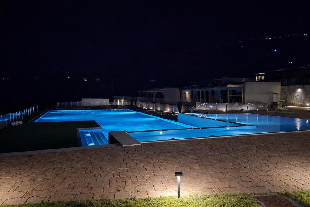 Piscina illuminata di notte con il solarium in pietra