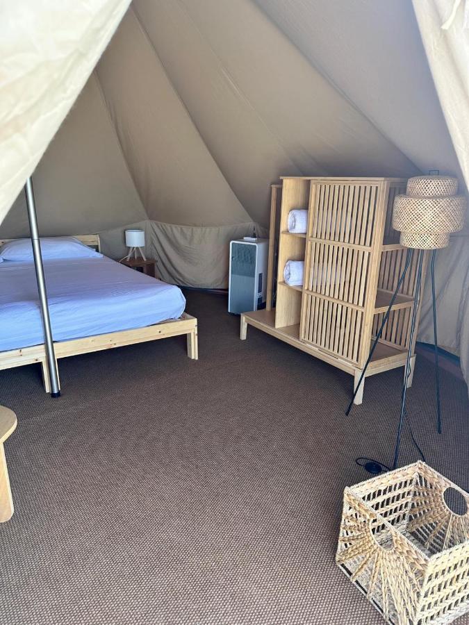 Interno della tenda glamping con letto king size e arredi in rattan
